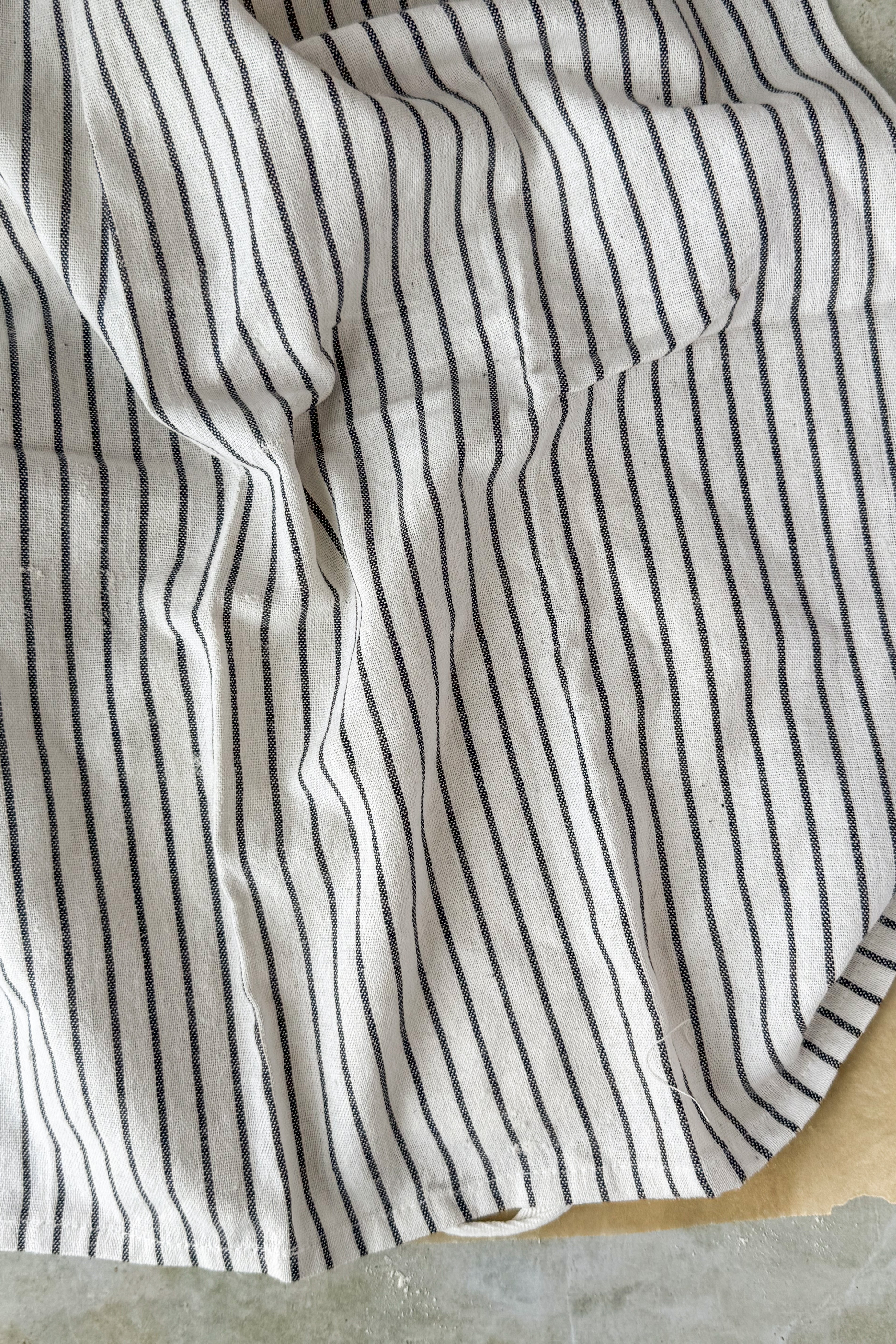 Black and white striped tea towel covered dough on parchment.
